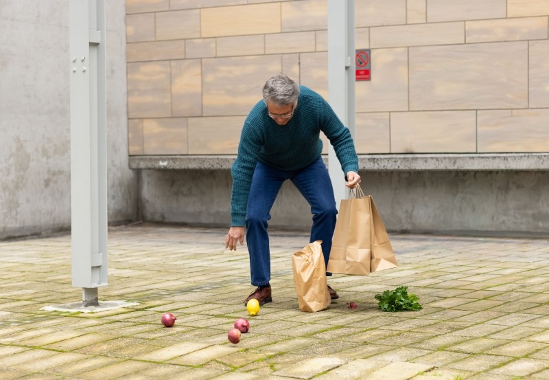 Man picking up fallen apples example of working memory outdoors.