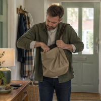 Man searching inside his bag near the front door.